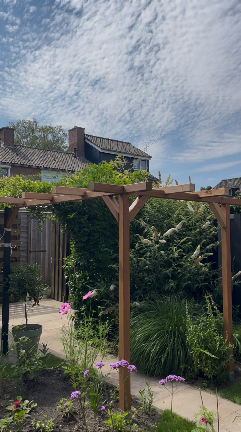 Houten pergola tussen bloeiende planten en siergrassen in een groene tuin